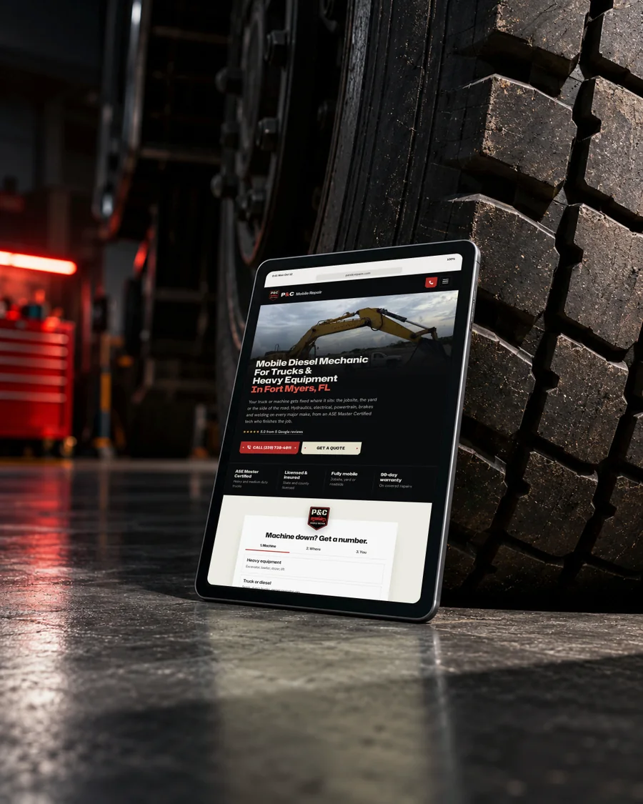 The P&C Mobile Repair website on a tablet leaning against a truck tire in a shop