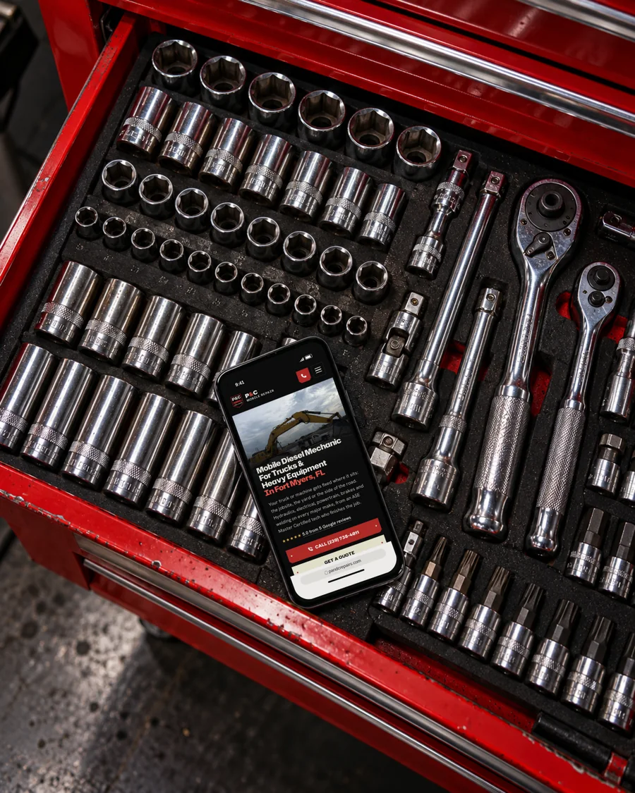 The P&C Mobile Repair website on a phone lying in a red tool chest drawer full of sockets